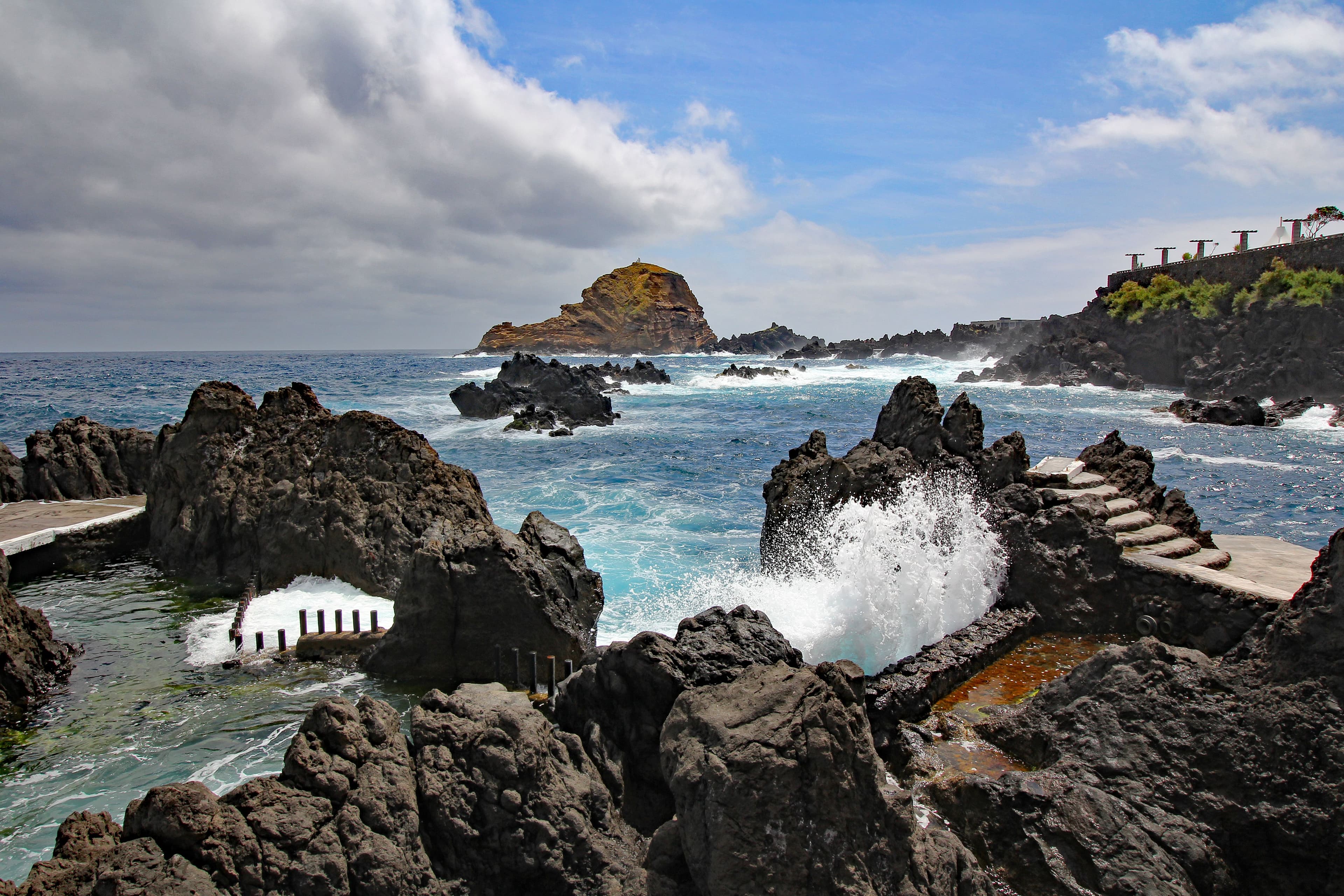 Atlantic waves wash over black lava rocks around the natural swimming pools of Porto Moniz.
