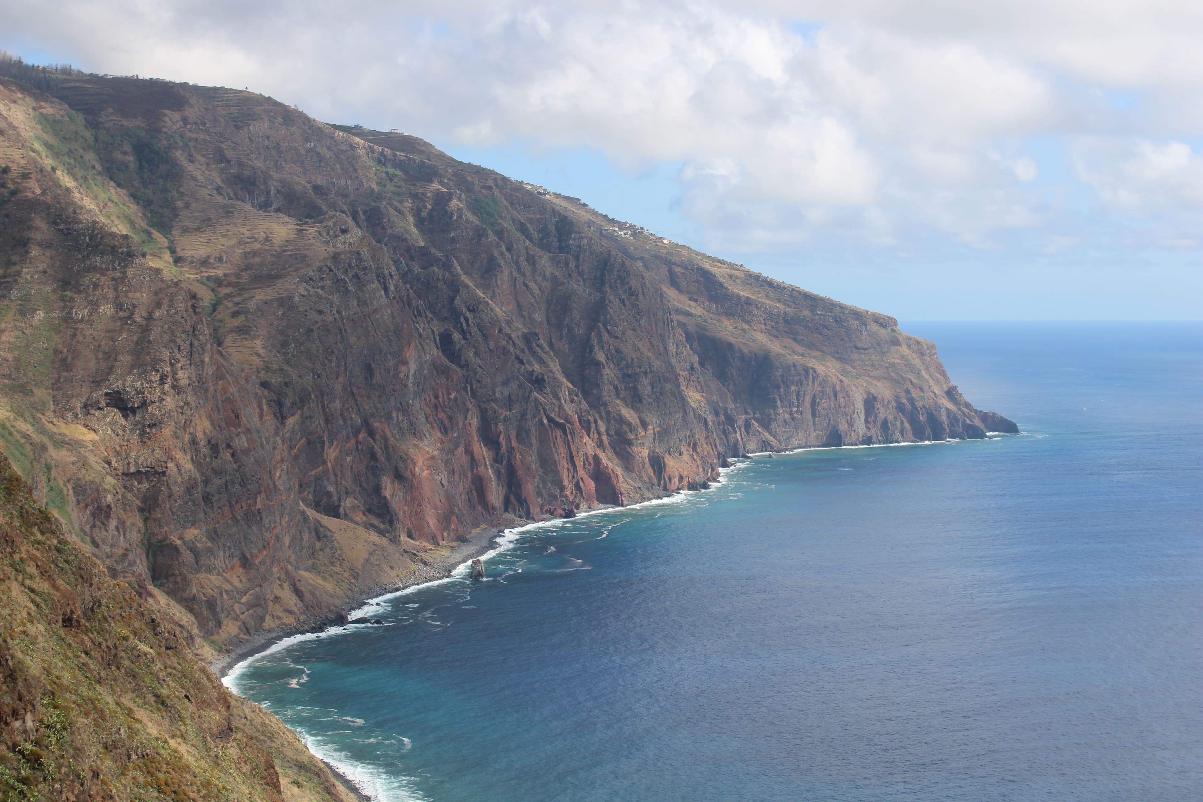Sheer green sea cliffs plunge into the deep blue Atlantic along Madeira’s rugged coastline.